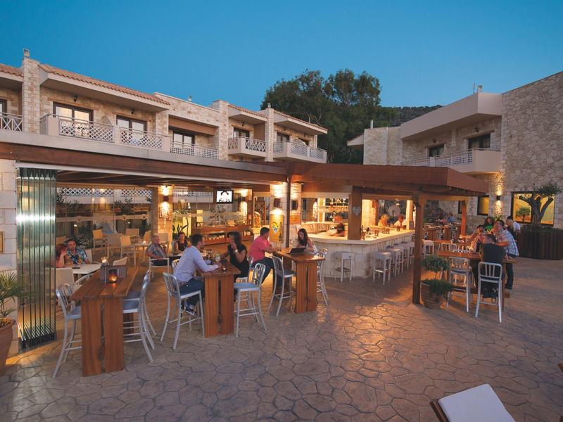 Terraza de hotel al atardecer con bares y personas disfrutando al aire libre.