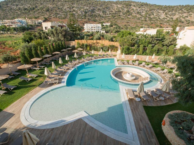 Piscina grande con forma única, tumbonas y sombrillas en un complejo hotelero.