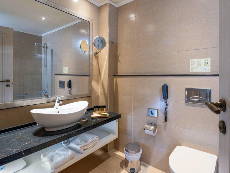 Baño moderno con lavabo sobre encimera oscura y espejo en la pared.