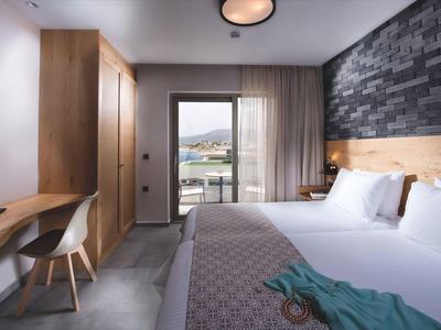 Modernes Hotelzimmer mit Doppelbett, Holzmöbeln, Schreibtisch und großem Fenster mit Blick.