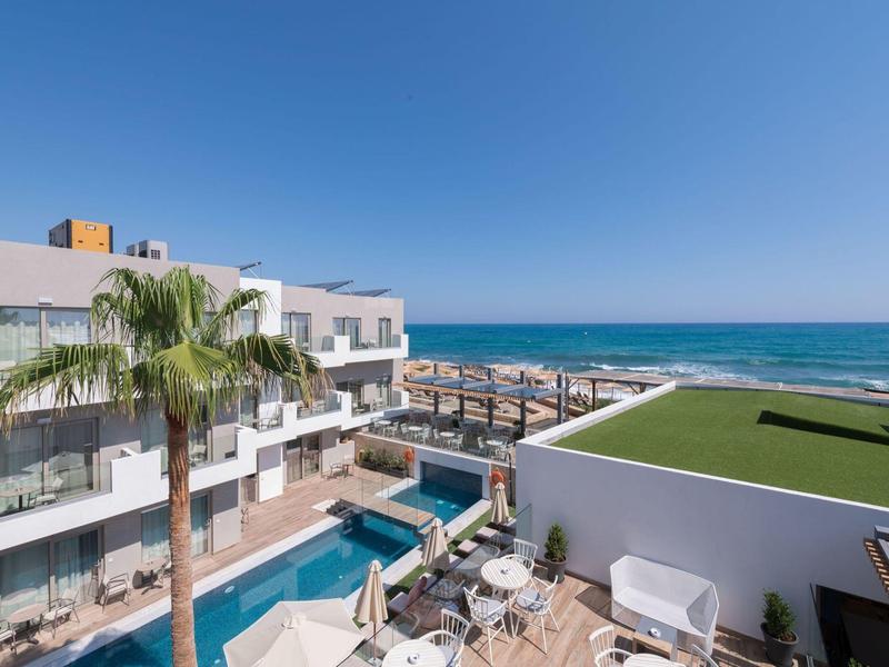 Hotel con piscina, palme e vista sul mare blu sotto un cielo sereno.