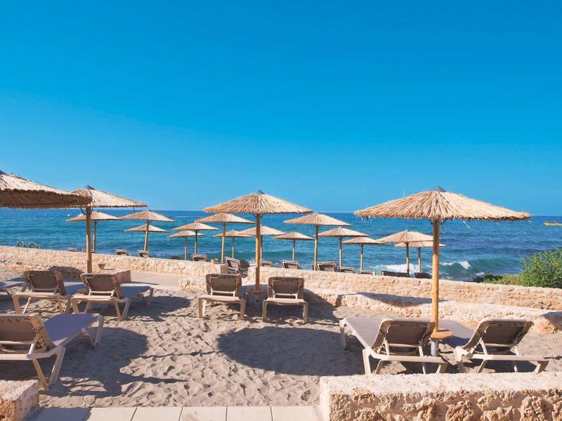 Spiaggia con lettini e ombrelloni accanto al mare calmo e blu.
