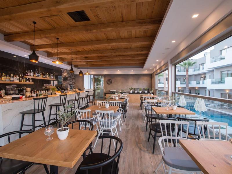 Ristorante moderno in hotel con mobili in legno e ampie finestre che si affacciano sulla piscina esterna.