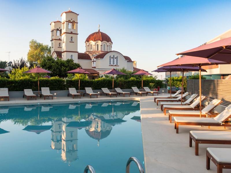 Clear swimming pool with loungers and distinctive church in the background under blue sky.