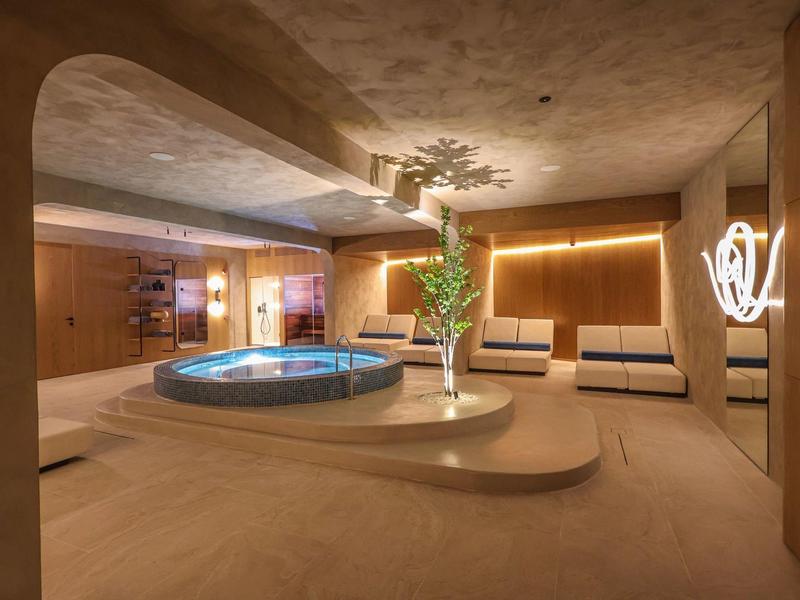 Modern wellness area with a hot tub, relaxing loungers, and warm lighting.
