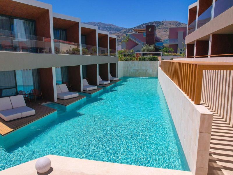 Modern outdoor pool with loungers and rooms directly adjacent to the water.