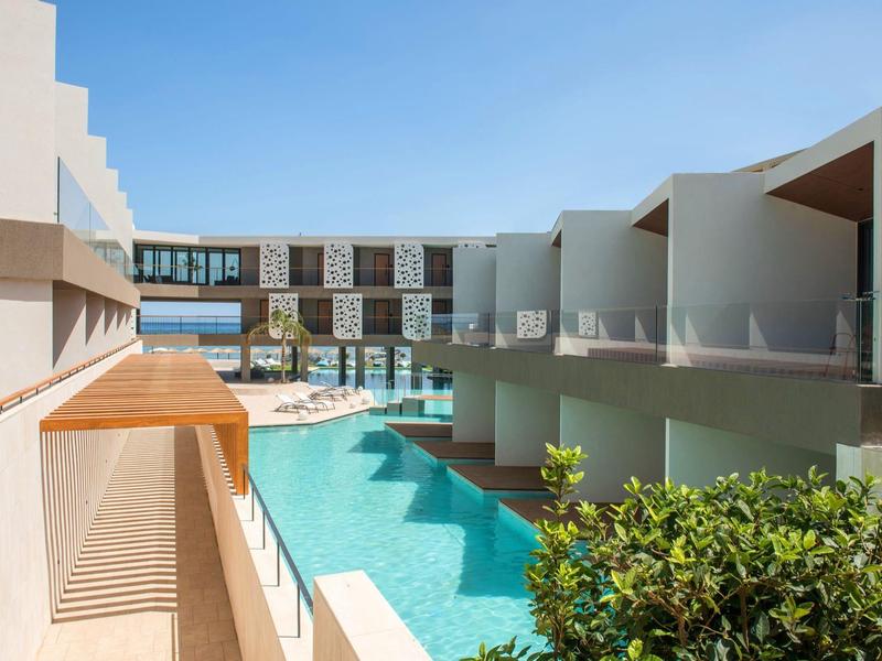 Modern hotel complex with pool between buildings under clear sky