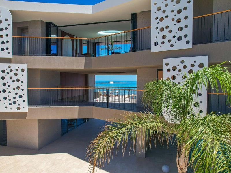 Modern hotel courtyard with palm trees and sea view