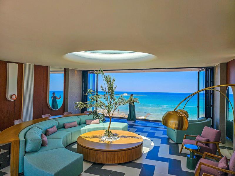 Modern lounge area with circular seating and ocean view through large windows.