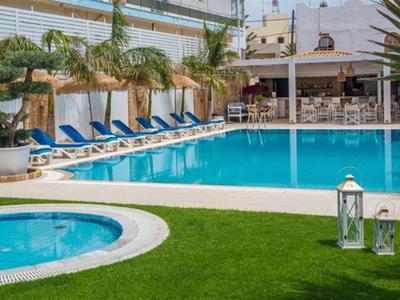 Hotelový bazén s lehátky vedle whirlpoolu a venkovního baru za slunečného počasí.