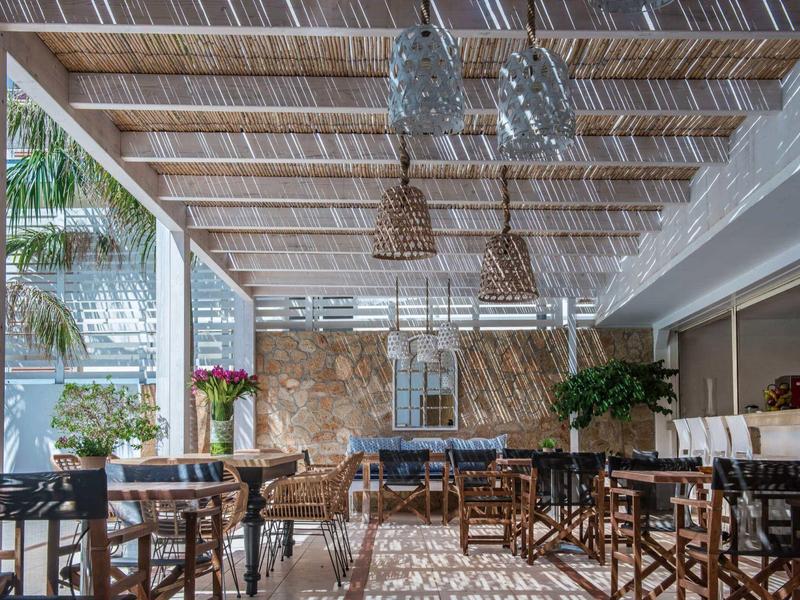 Otevřená jídelna s dřevěným nábytkem a přirozeným světlem skrz filtrovanou střechu