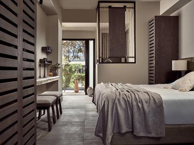 Modernes Schlafzimmer mit Holzakzenten, grauer Bettdecke und Zugang zu einem Garten im Hintergrund.