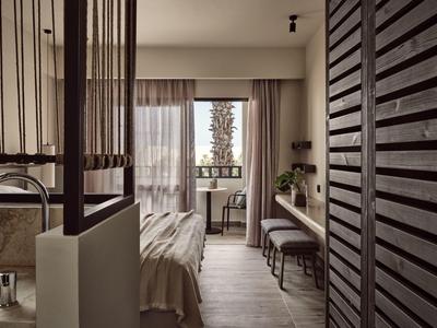 Modernes Schlafzimmer mit großem Fenster, Tisch, Stuhl, gemütlichem Bett und Holzlamellen-Tür.