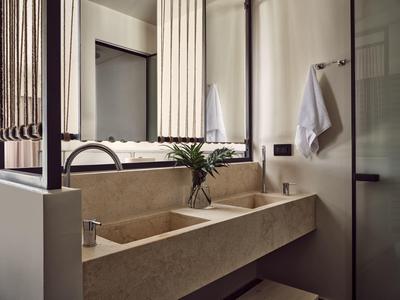 Moderner Doppelwaschtisch aus Stein mit Ablage, Spiegeln und Handtüchern im minimalistischen Bad.