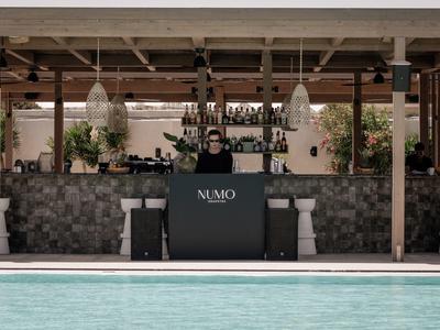 Persona in piedi dietro un bancone con insegna nera vicino alla piscina in un'area aperta.