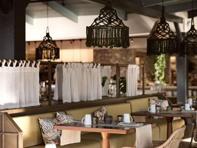 Moderne Cafeteria mit Holztischen, Stoffservietten und dekorativen Lampen in warmem Licht.