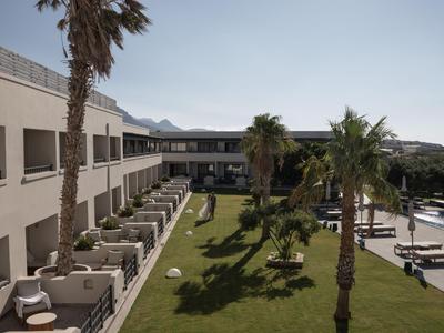 Vista su un giardino dell'hotel con palme e un edificio a due piani sotto un cielo sereno.