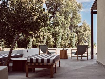 Zona esterna moderna con sedie e divano sotto gli alberi in una giornata di sole