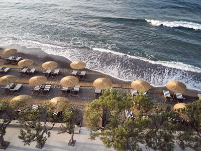 Spiaggia con ombrelloni e lettini accanto al mare in una giornata nuvolosa.
