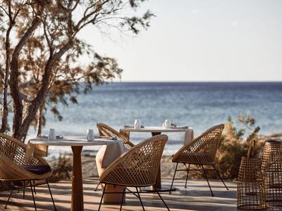 Cozy wicker chairs and tables on a terrace overlooking the sea.