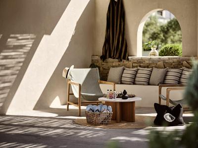 Cozy terrace with lounge area, wooden furniture, and cushions in warm light.