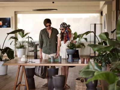 Two people explore a bright, modern hotel lobby with plants.