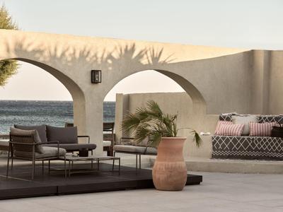Modern outdoor area with white arches, comfortable seating, and a sea view.