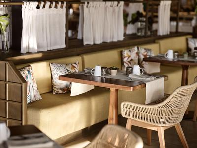 Cozy hotel lounge with yellow sofa, cushions, wicker chair, and set table.