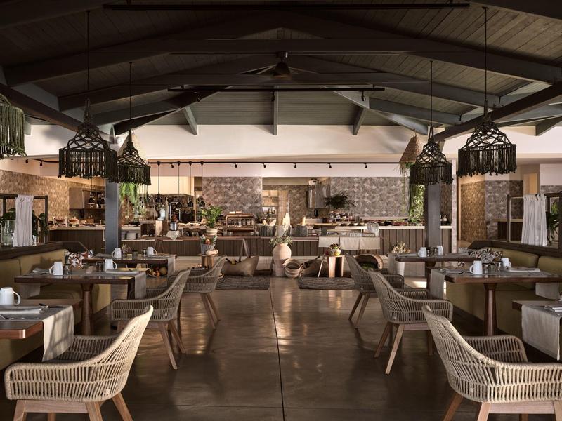 Großes, modernes Restaurant mit Holzmöbeln, geflochtenen Stühlen und warmem, gedämpftem Licht.