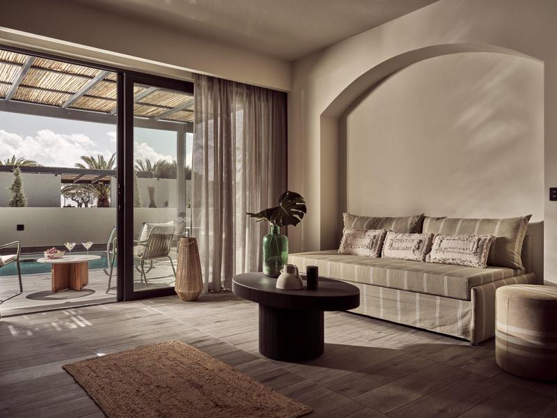 Gemütliches Wohnzimmer mit Sofa, rundem Tisch, Teppich und großer Glas-Schiebetür zum Balkon.