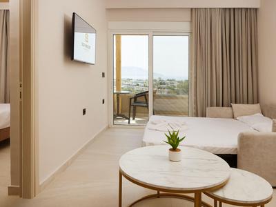 Modern hotel room with balcony, table, and plants in neutral tones.