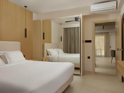 Modern hotel room with double bed, light wood, and large mirror.