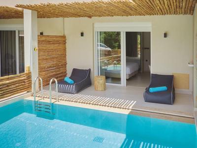 Terrace with pool, two armchairs, and bamboo sunshade in front of hotel room