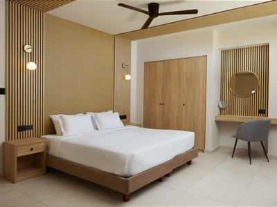 Modern hotel room with large bed, wooden panels, and a seating area.