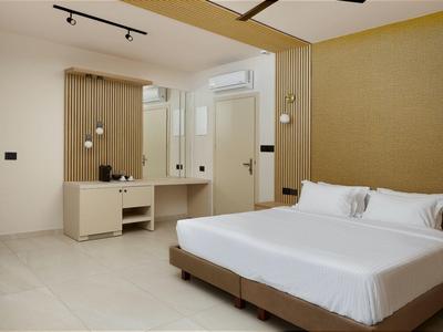 Modern hotel room with large double bed and desk with mirror.