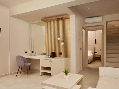 Modern living area with sofa, TV, desk, and view into the bedroom.