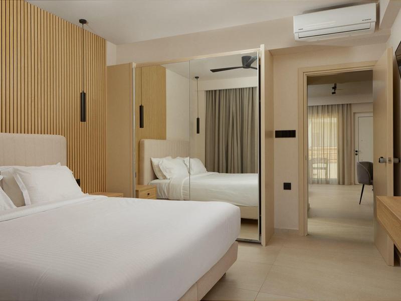 Modern hotel room with double bed, light wood, and large mirror.