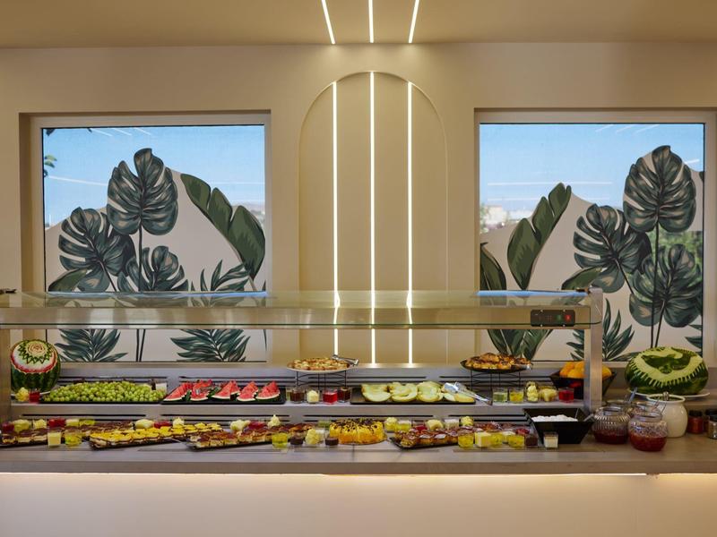 Buffet display with various fruits and decorative plants in the background.