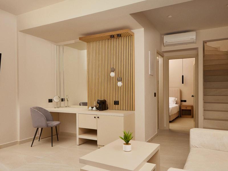 Modern living area with sofa, TV, desk, and view into the bedroom.