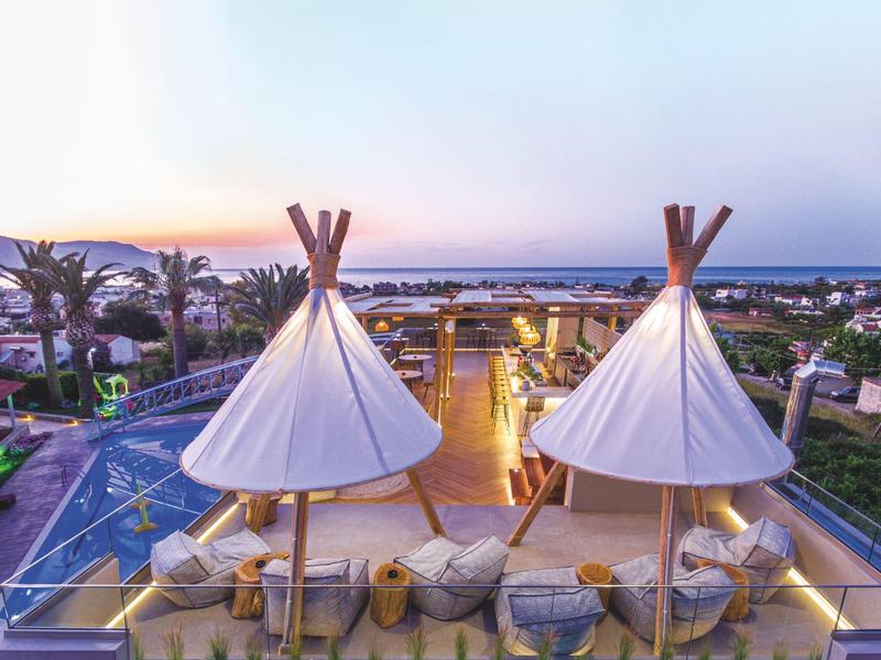 Hotel terrace with two white tipis, pool view and seating area at sunset.