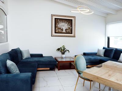 Helles Wohnzimmer mit blauen Sofas, Holztisch, modernen Stühlen und großem Fenster.