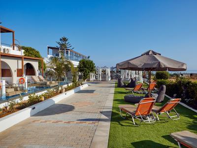 Hotelgarten mit Liegestühlen und Sonnenschirmen bei klarem Himmel.