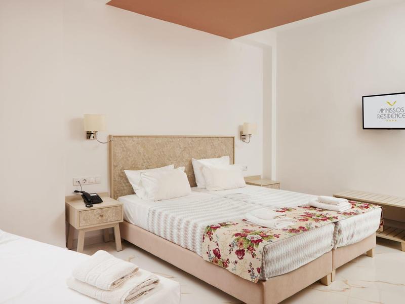 Habitación de hotel luminosa con cama doble, mesitas de noche, lámparas de pared y cuadro enmarcado en la pared.