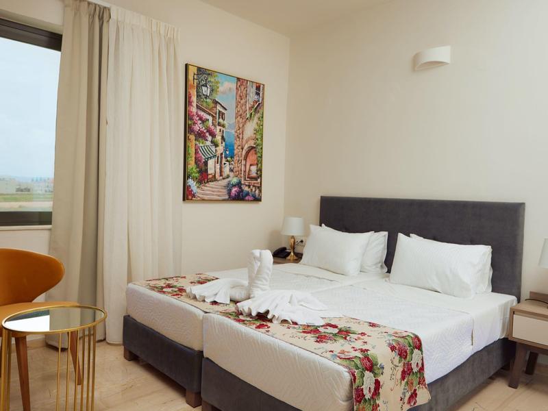 Habitación de hotel moderna con dos camas individuales, suelo de madera clara y arte en la pared.