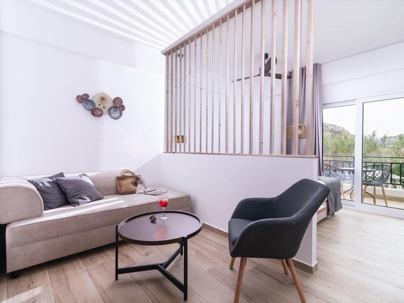 Modern woonkamer met grijze bank, salontafel en stoel nabij balkon met uitzicht.