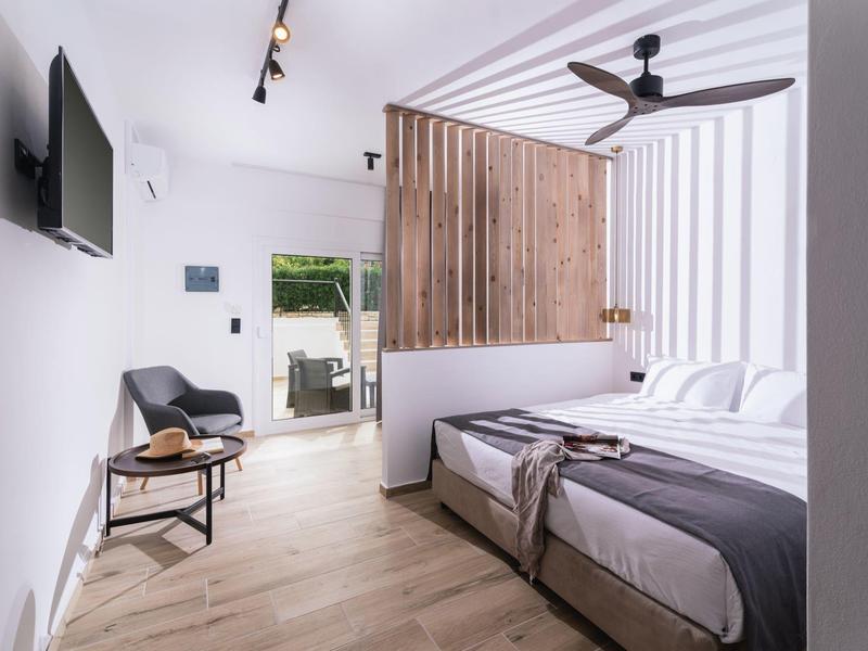 Modern ingerichte slaapkamer met tweepersoonsbed, houten vloer en tv aan de muur.