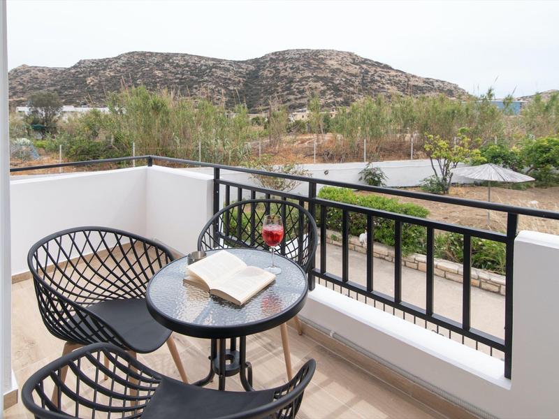 Balkon met twee stoelen, een tafel en een open boek met uitzicht op heuvels.