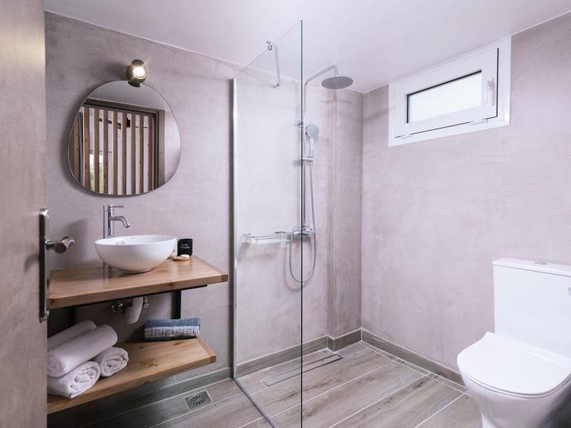 Moderne badkamer met inloopdouche, houten plank, ronde spiegel en toiletruimte.