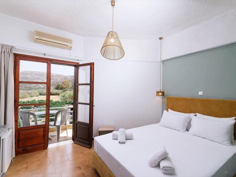 Lichte hotelkamer met tweepersoonsbed, balkon en uitzicht op het platteland.