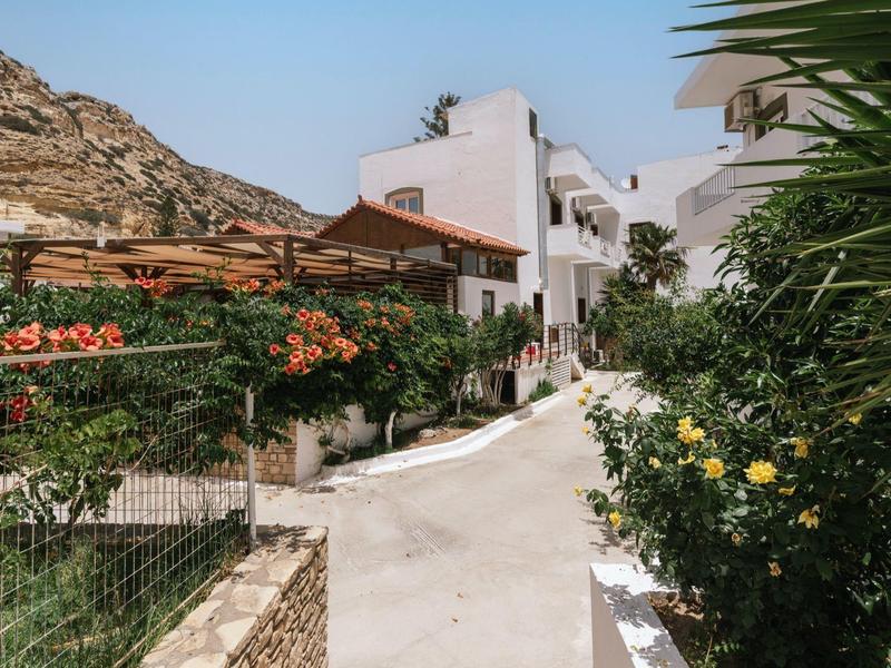 Wit hotelgebouw met eetgedeelte en bloeiende planten in zonnig berglandschap